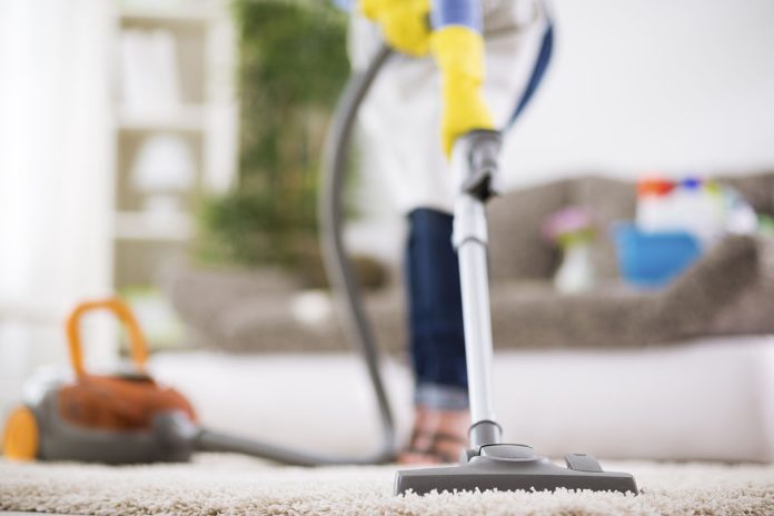 Woman vacuums carpet professional upholstery cleaning